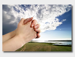 Praying hands against dramatic landscape